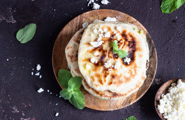 Onion, mint and cheese small flatbreads served on a wooden plate. Gozleme - crispy, golden Turkish flatbreads.