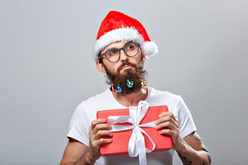 Christmas, holidays, barbershop and style concept - young handsome bearded santa claus man with many small christmas baubles in long beard