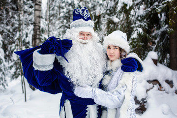 Russian Christmas characters Ded Moroz (Father Frost)  and Snegurochka (snow maiden) in a snowy forest.
