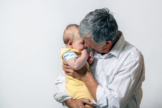 The Grandfather And The Baby. An Old Man Holding His Grandson In His Arms