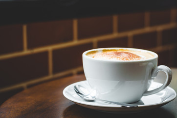 close up modern hot black coffee the cappuccino on wood background with coffee bubble foam pattern and texture in white cup looking and feel so delicious on glasses table in coffee shop.