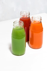 colorful vegetable juices in bottles on white background, vertical top view