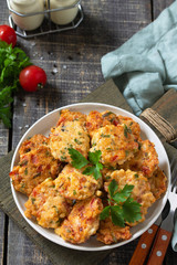 Chicken meatballs with minced meat with tomatoes in a bowl on a wooden rustic table.