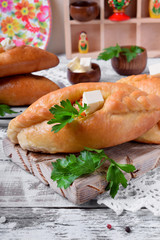 Rasstegai pie of yeast dough with meat filling on white wooden table. Traditional meal of Russian cuisine