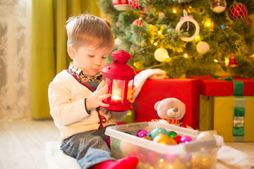 Fototapeta na wymiar Cute little boy child decorating Christmas tree in room. Christmas or New Year holiday