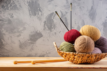 Skeins of yarn for knitting from natural wool in a wicker basket. Wooden surface or table....