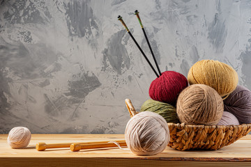 Skeins of yarn for knitting from natural wool in a wicker basket. Wooden surface or table....