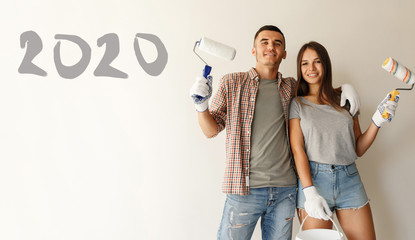 Young couple ready to painting wall. painters with paint roller