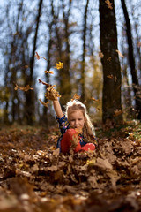 Amazing leaf. Cute girl in a big pile of foliage. Small girl smile sitting on fall leaves. Little child girl enjoy playing on fresh air