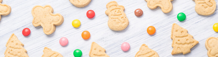 Christmas cookies of different shapes and candies on a light gray background, long photo