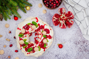 Caramel Pavlova Christmas wreath with cherry sauce, pomegranate, cranberries and kiwi on a light stone background. Festive dessert for Christmas and New Year.