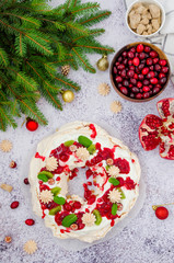 Caramel Pavlova Christmas wreath with cherry sauce, pomegranate, cranberries and kiwi on a light stone background. Festive dessert for Christmas and New Year.