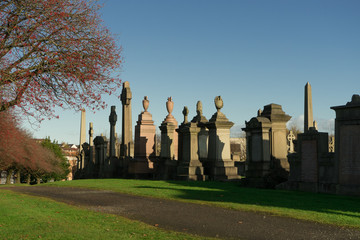 The sunny autumn day of the old Victorian cemetery Necropolis in United Kingdom photographed from afar with the sun backlight. Religion and death theme. Glasgow, Scotland 