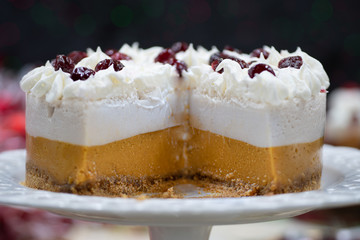 Christmas pumpkin and cranberry mousse on cake stand, on a festive table