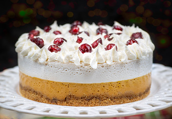 Christmas pumpkin and cranberry mousse on cake stand, on a festive table