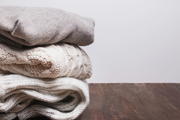 Pile of warm knitted sweaters on the wooden table