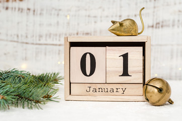 Chinese New Year 2020. Date January 1 on a wooden calendar with metal rat and christmas bell and twigs of a Christmas tree on a white background. New Year of the rat.
