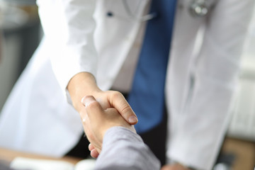 Closeup image of healthcare professional or doctor or dentist shaking hands with patient.