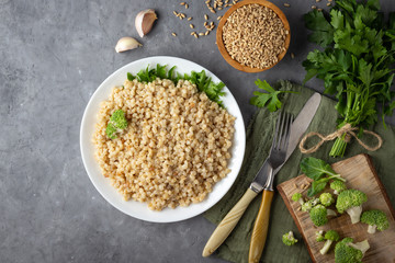 Boiled spelt on a plate. Healthy food. Gray concrete background. Top view with copy space.