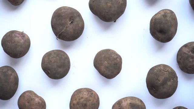 Slowly zooming in of dirty potatoes on a white background
