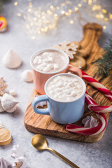 Hot chocolate cacao drinks with marshmallows in Christmas color mugs on grey background. Traditional hot beverage, festive cocktail at X-mas or New Year