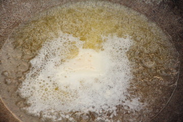 Cooking outdoor, heated boiling butter oil in Kazan close up
