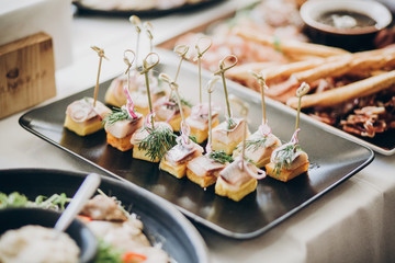 Delicious food table at wedding reception. Fish finger appetizers with onion on table at wedding or...