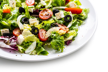 Fresh greek salad on a plate on white background