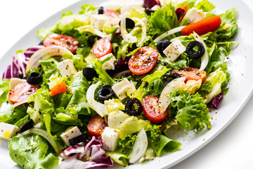 Fresh greek salad on a plate on white background