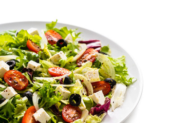 Fresh greek salad on a plate on white background