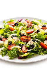 Fresh greek salad on a plate on white background