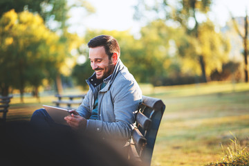  Handsome middle aged businessman using tablet while sitting in a park