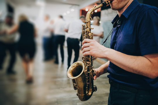 Musician playing sax at wedding reception in restaurant. Man performing jazz song on saxophone at party or wedding. Space for text. Jazz music concept