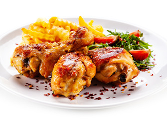 Roast chicken drumsticks with french fries and vegetables on white background