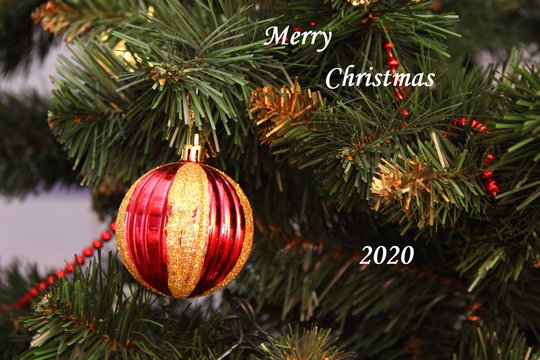 Pine branch with Christmas ball and inscription Merry Christmas 2020
