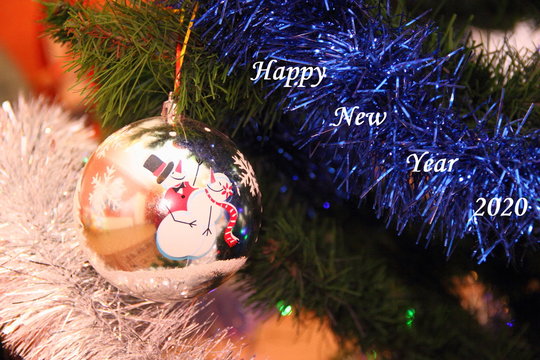 Fir branch tinsel with Christmas ball with dancing snowmen and inscription Happy new year 2020