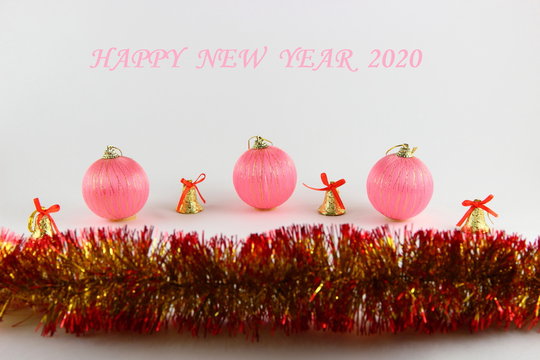 Happy new year 2020 pink text with pink  Christmas balls, yellow bells and yellow red tinsel