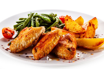 Fried chicken wings with baked potatoes and green beans