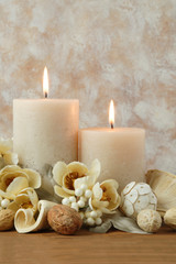 Fototapeta na wymiar Spa concept of burning cream colored candles arranged with natural potpourri elements and flowers on a warm background