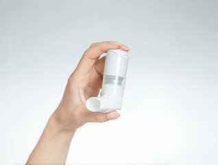 Woman's hand holding a medical asthma inhaler.
