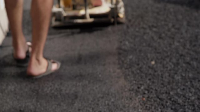 Close-Up Worker In Slippers Tamping Fresh Asphalt
