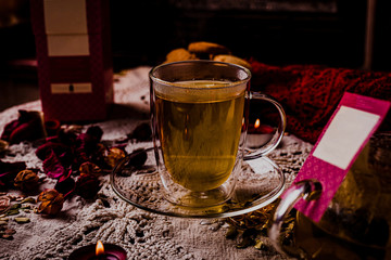 Hot tea or coffee in a red mug, ginger cookies on vintage wood table. Fireplace as background. Christmas or winter warming drink. Layout with free text space.