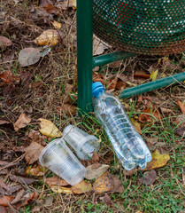 Obraz premium plastic bottle and plastic glasses near the trash can