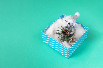 Cute little rat or mouse is sitting in blue gift box on mint background. Present and symbol for New Year and Christmas.