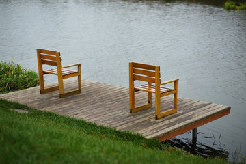 Fototapeta premium Empty wooden chairs at the river bank dock, landscape design