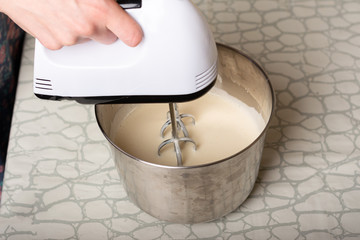 kneading the cake dough in a metal bowl with a mixer
