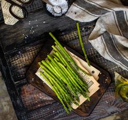 fresh green asparagus on wooden board stands on rustic wooden table 