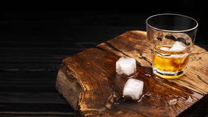 A glass of alcoholic beverage on a wooden table. Whiskey cocktail with ice top view