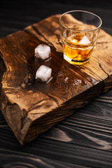 A glass of alcoholic beverage on a wooden table. Whiskey cocktail with ice top view