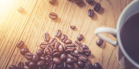 Close up of fresh roasted coffee beans and coffee mug on wooden background